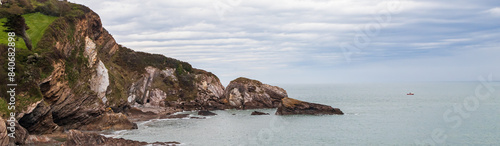 Seascape with a rocky shore. Wide panoramic view, banner with rocky sea coast landscape and cloudy sky