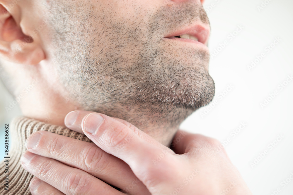 Fototapeta premium young male neck, man patient holding affected area, experiencing throat pain, Health concern, loss of voice, various causes, tonsillitis