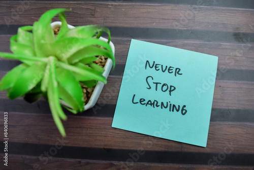 Concept of Never Stop Learning write on sticky notes isolated on Wooden Table. photo