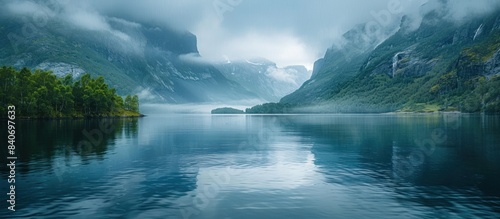 A serene lake in Norway surrounded by misty mountains and lush green forests. photo