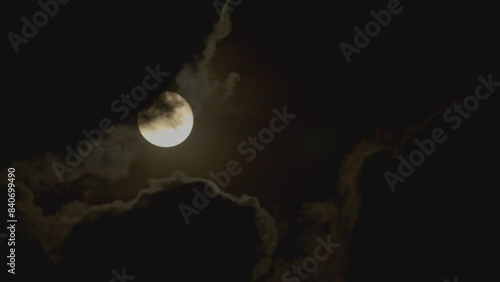 Full moon in the night sky with clouds flying across it