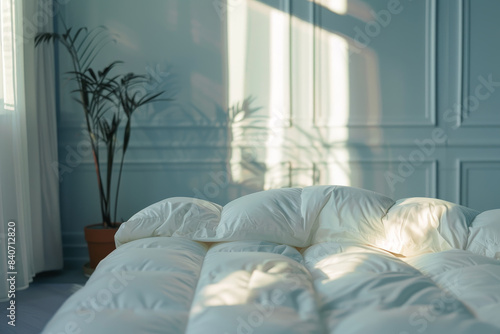 A white bed with a white comforter and a white pillow
