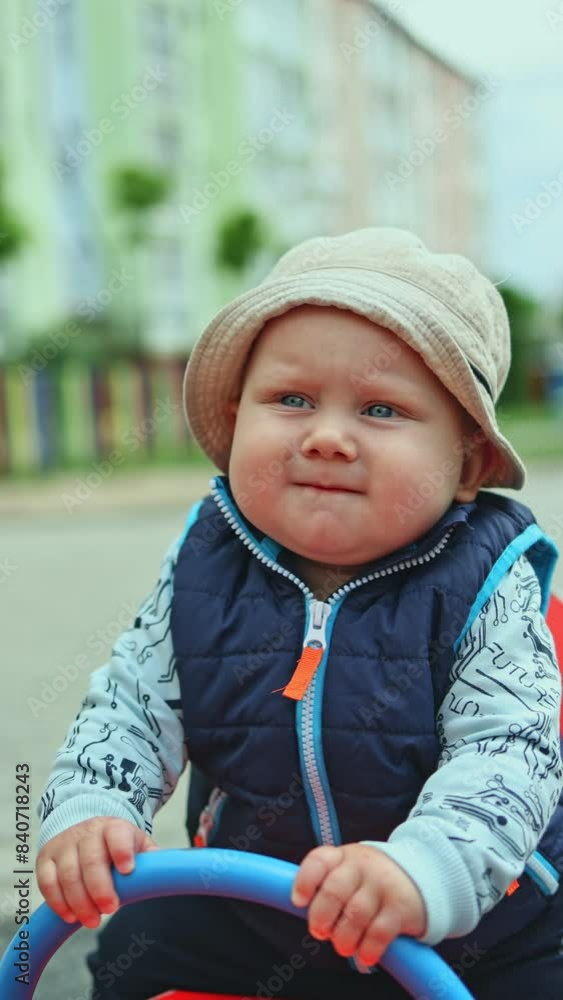 A small child rides on a swing. A 10-month-old boy is playing on the playground outside. A small child rides on a swing. A 10-month-old boy is playing on the playground outside.