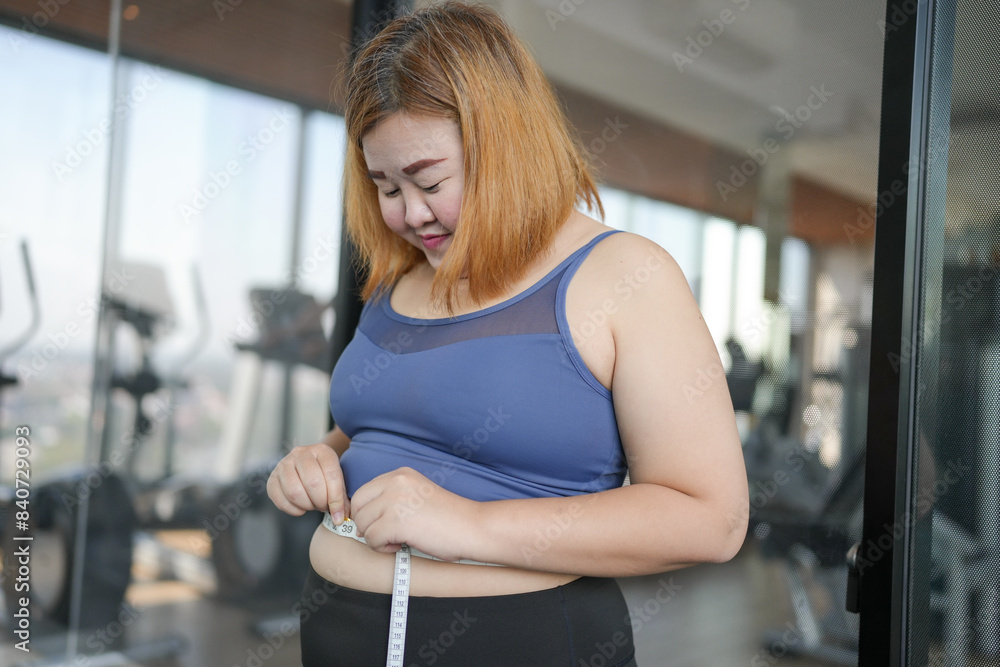 Obraz premium Obese Woman with fat belly in dieting concept. Overweight woman touching his fat belly and want to lose weight. Fat woman waist with centimeter Shape up healthy stomach muscle.
