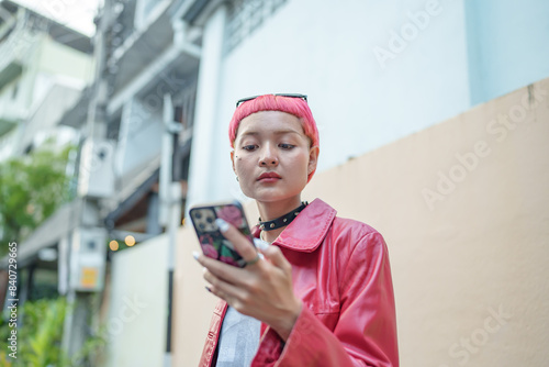 Traveler Gen z girl leather fashion with punk Asian woman tourist in city street searching location in map application online smart phone using GPS navigating