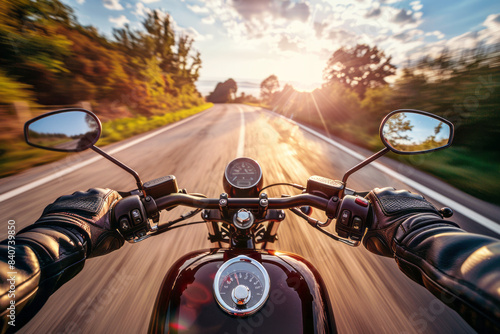 Motorcyclist riding on an empty asphalt road with sunset in the background, view from the motorcyclist's perspective
