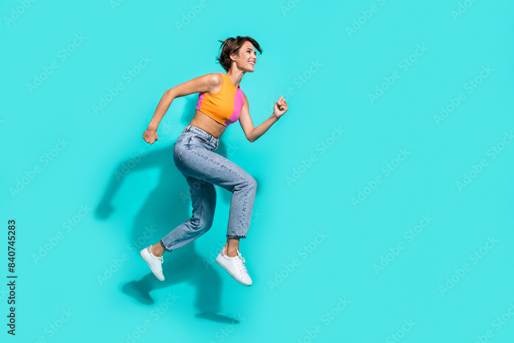 Full length photo of hurrying excited woman wear pink orange top jumping high running fast empty space isolated teal color background
