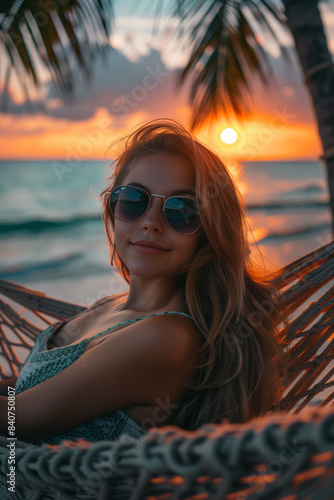 Caucasian woman lying in a hammock at sunset on a tropical beach. © S photographer