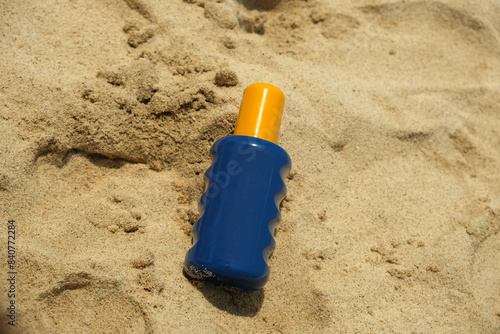 blue bottle with yellow cap on the sand