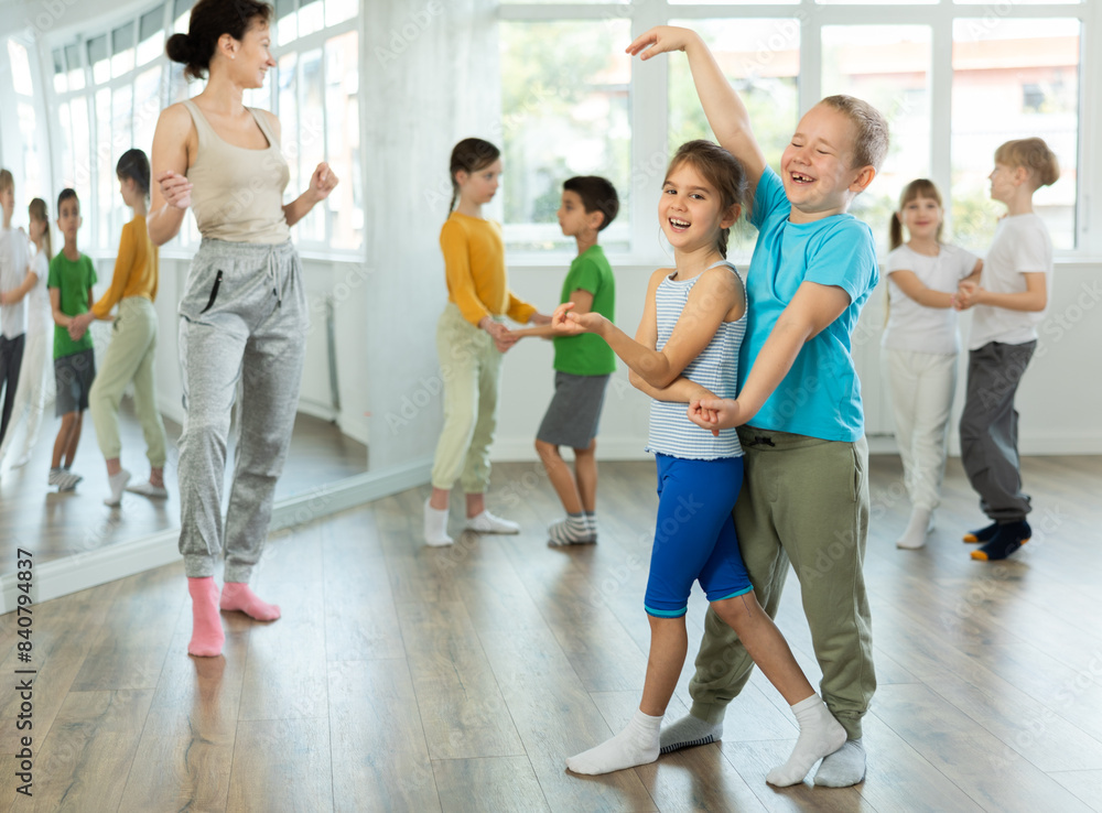 Fototapeta premium Positive preteen children learning to dance waltz in pairs in choreography class