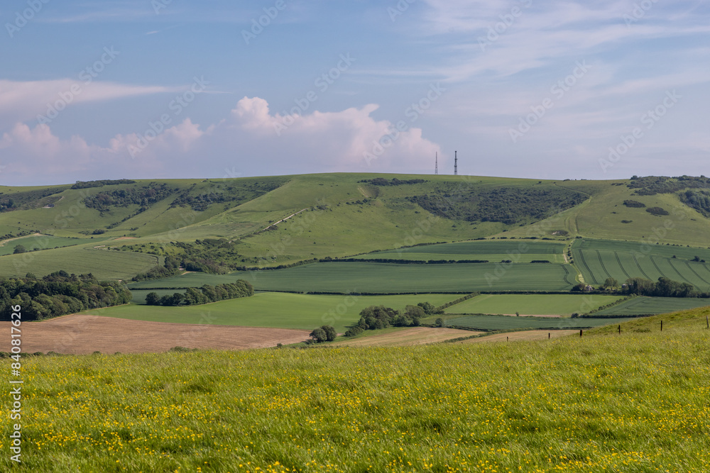 A rural Sussex view towards Firle Beacon in the South Downs, with a blue sky overhead
