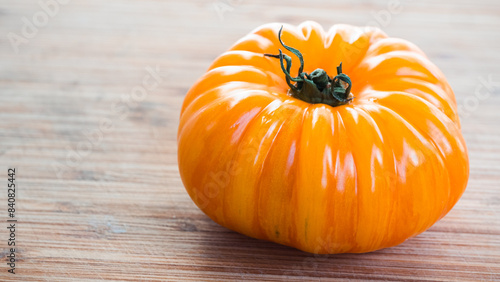 Bright orange colored gourmet  tomato sitting on the right side of the frame. Leaving the left side available for adding text.
Captured in a highly detailed close up. Harvesting season concept.