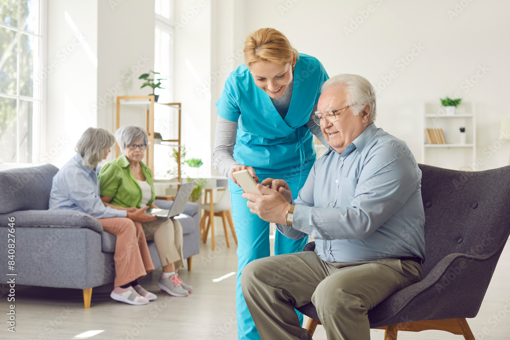 Obraz premium Positive caring kind smiling nurse, geriatric medicine caretaker providing senior man help with phone to support aged old during medical visit in retirement home, female doctor caregiving service 