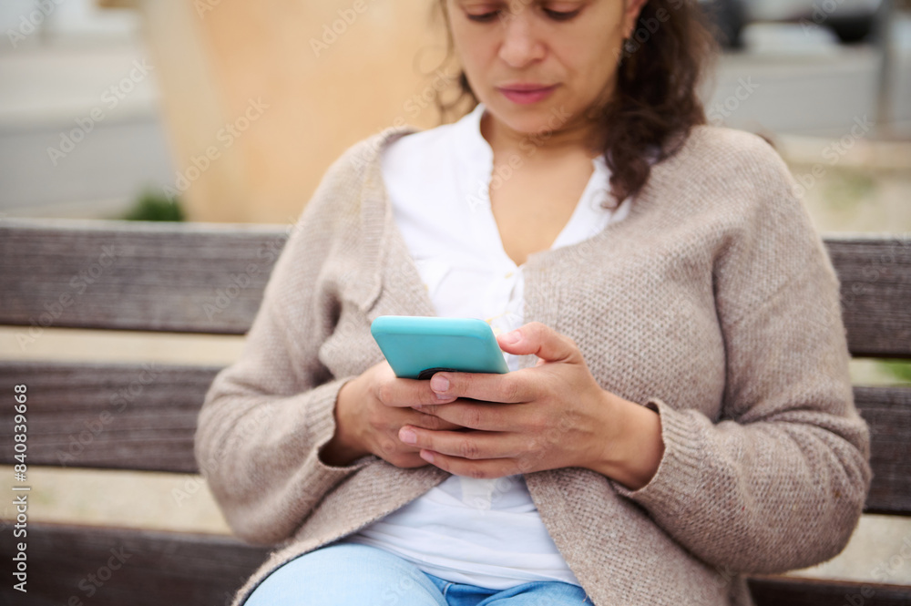 Portrait of a woman using mobile phone outdoors, sitting on a city bench Portrait of a woman using mobile phone outdoors, sitting on a city bench