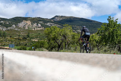 Cyclist running up to the mountain with the old medieval castle in spanish Pyrenees mountains
