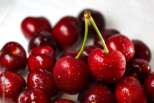 A bunch of cherries are arranged on a clean white tabletop