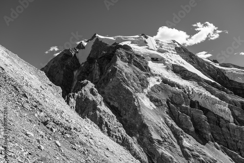 The towering Ortles Mountain stands grand under blue skies, its snowy caps and rugged terrain evincing the serene beauty of the Italian Alps. Black and white photography. photo