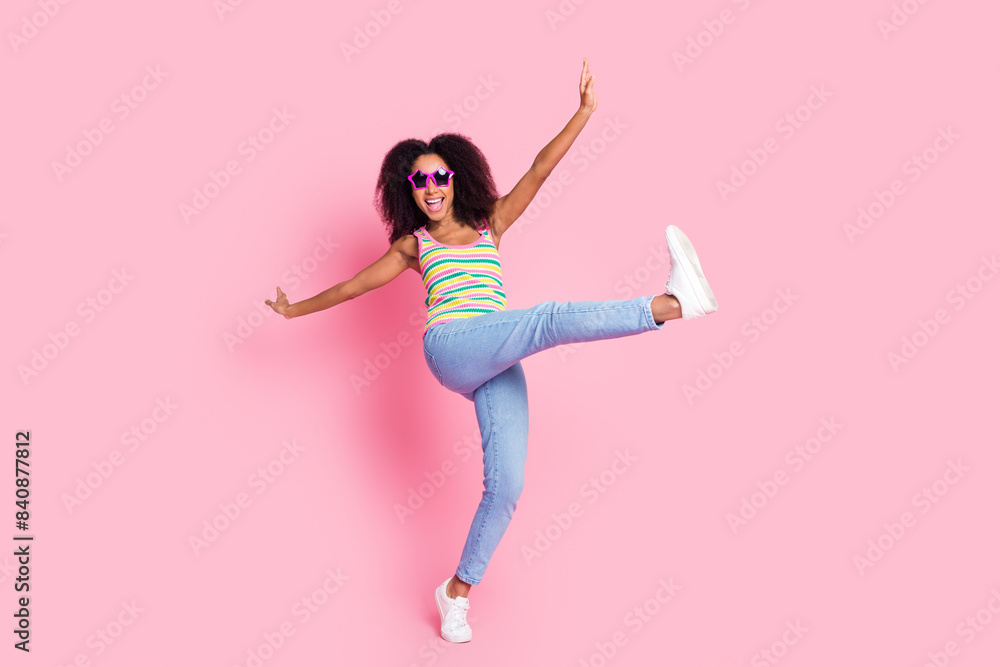 Full size photo of ecstatic woman dressed knit tank jeans pants in glasses dancing raising leg up isolated on pink color background Full size photo of ecstatic woman dressed knit tank jeans pants in glasses dancing raising leg up isolated on pink color background
