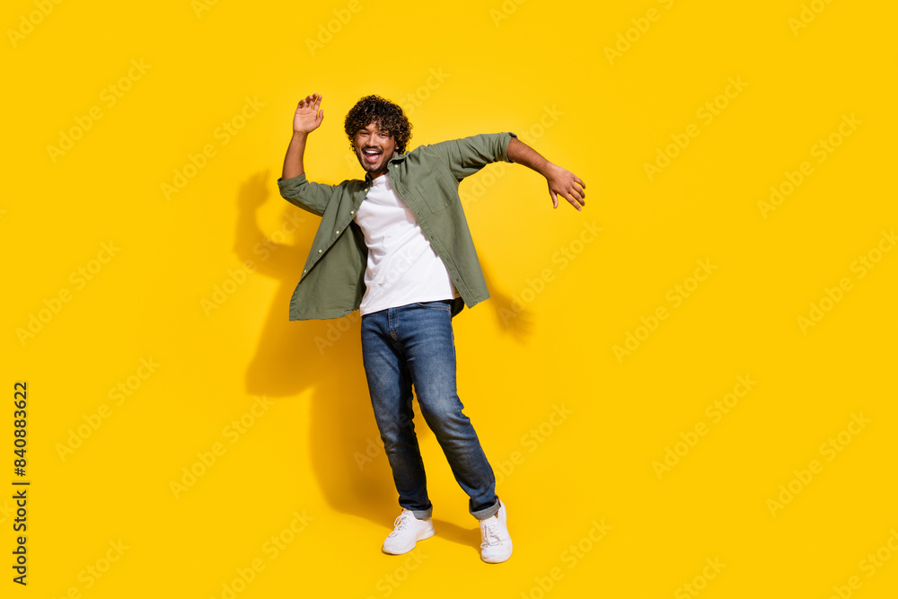 Fototapeta premium Portrait photo of young funny mexican guy in khaki shirt dancing boogie woogie at hipster party isolated on yellow color background