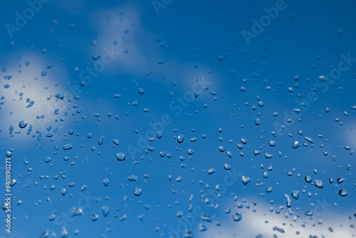 bellissima composizione macro che mostra delle goccioline di pioggia su di un vetro trasparente in primo piano e il cielo azzurro brillante sfuocato sullo sfondo, dopo un temporale