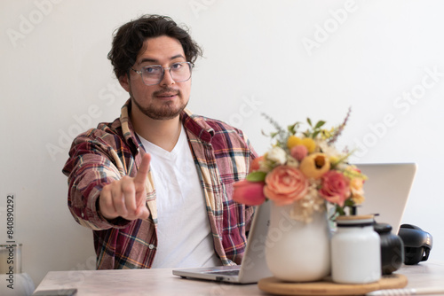 Young man with glasses from his laptop making gesture and wellness vibes concept in the living room