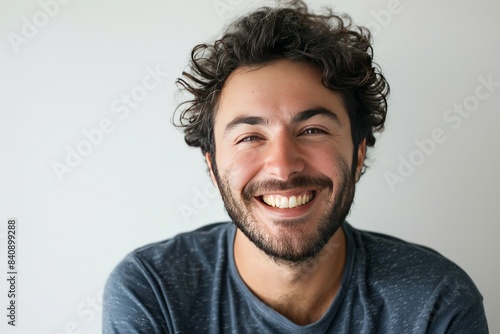 Warm and engaging portrait of a man with curly hair smiling, depicting relaxed happiness