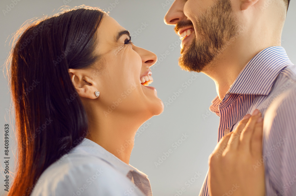 Naklejka premium Close up portrait of a happy smiling affectionate young couple man and woman looking at each other and hugging isolated on gray background. Care, love, tenderness and Valentines day concept.