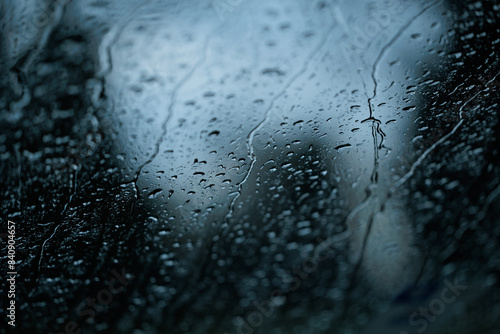 gocce di pioggia sul vetro trasparente di un'auto su sfondo sfuocato misto chiaro scuro photo