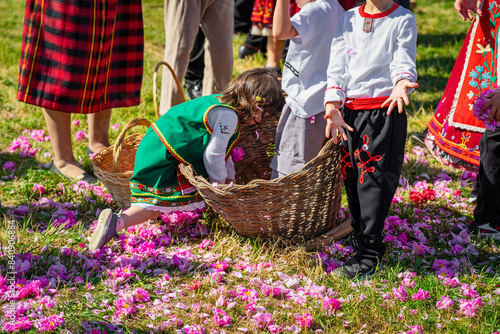 Fototapeta Naklejka Na Ścianę i Meble -  Children dressed in traditional dress with basket of rose petals having fun, playing during Rose Festival in Bulgaria