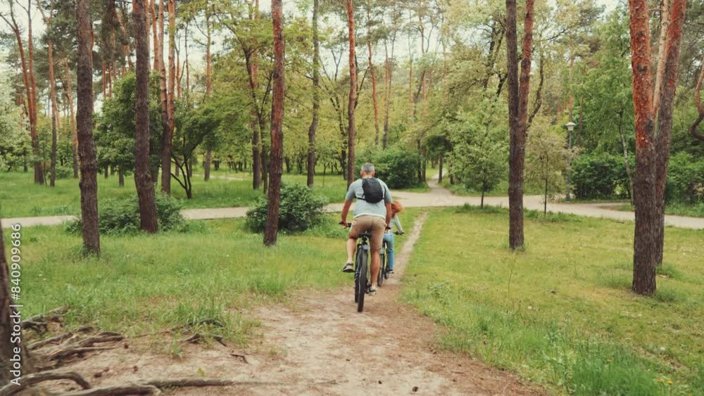 Couple biking through forest path, enjoying outdoor activity together. Man and woman from behind, navigating dirt path surrounded by lush greenery and trees. Concept of leisure and nature exploration Couple biking through forest path, enjoying outdoor activity together. Man and woman from behind, navigating dirt path surrounded by lush greenery and trees. Concept of leisure and nature exploration