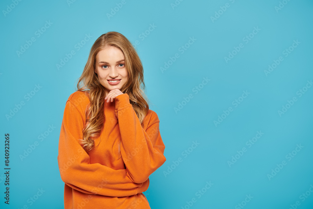 A stylish woman with blonde hair posing on bright blue backdrop. A stylish woman with blonde hair posing on bright blue backdrop.