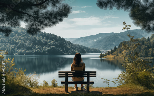 A woman sits on a bench overlooking a lake