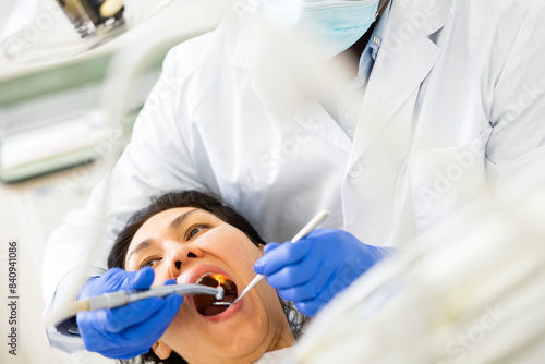 Dentist examining oral cavity of asian woman patient with special tools in dental clinic.