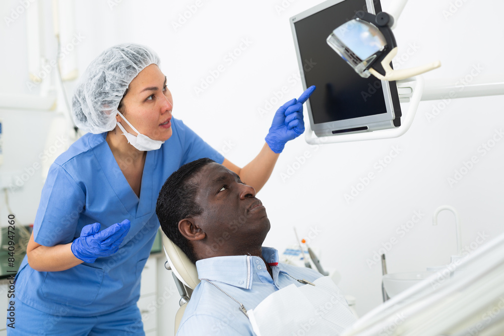 Obraz premium Doctor dentist shows patient an x-ray on computer