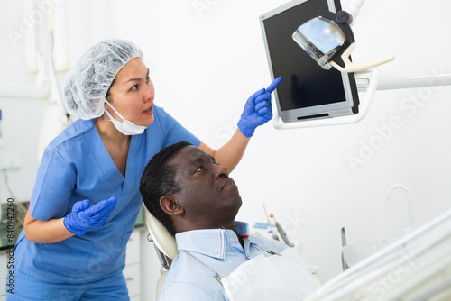 Doctor dentist shows patient an x-ray on computer