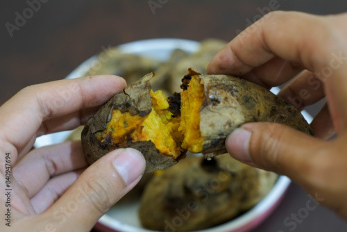 Hand hold Ubi bakar madu cilembu or Cilembu honey roasted sweet potato. it tastes good, sweet honey and soft, traditional food Indonesia. photo