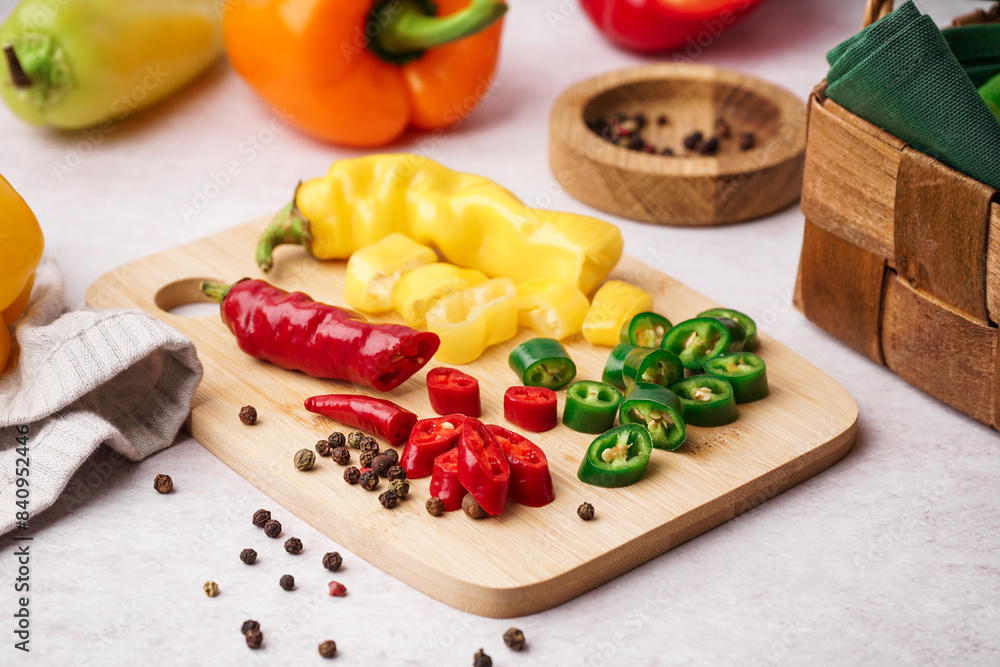 Wooden board with cut chili peppers and peppercorn on white background Wooden board with cut chili peppers and peppercorn on white background