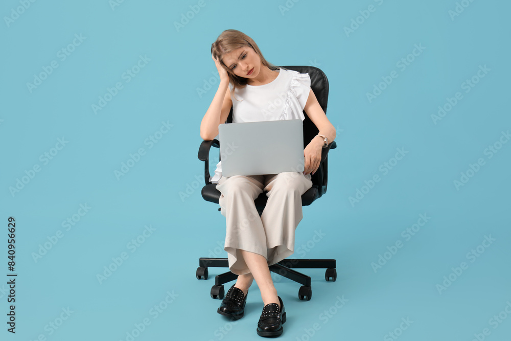 Tired young woman with laptop sitting on office chair against blue background Tired young woman with laptop sitting on office chair against blue background