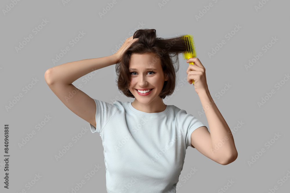 Beautiful young happy woman with bob hairstyle holding brush on grey background Beautiful young happy woman with bob hairstyle holding brush on grey background