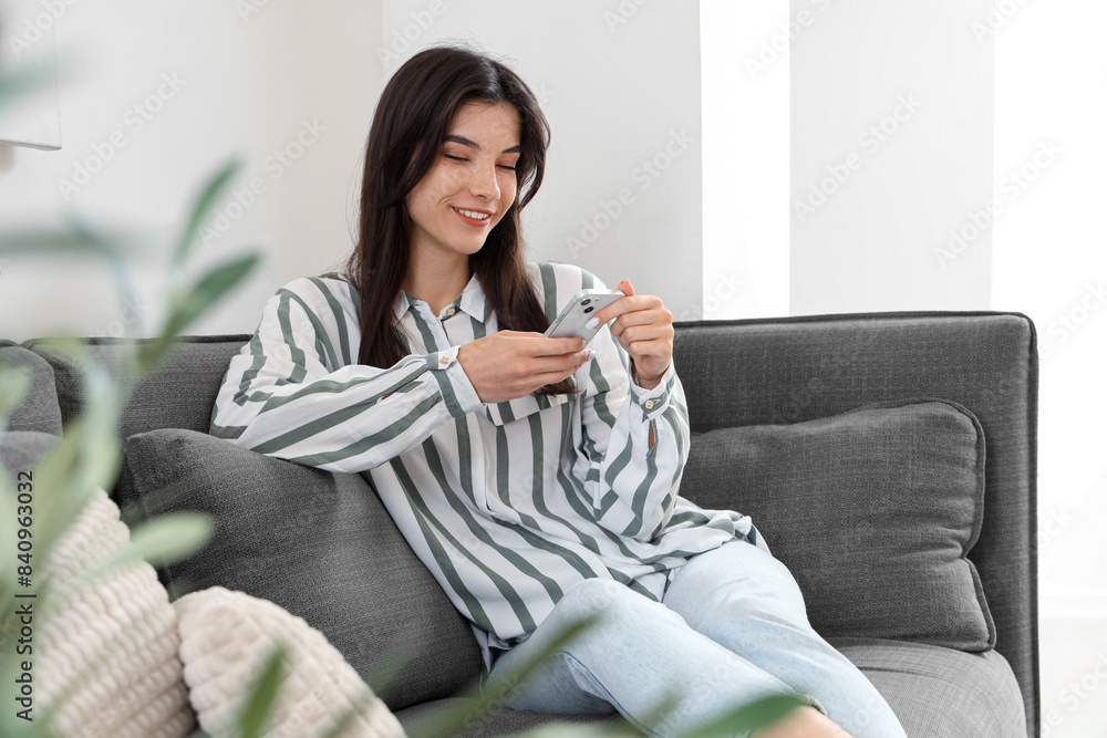 Young woman with cup resting on black sofa in living room Young woman with cup resting on black sofa in living room