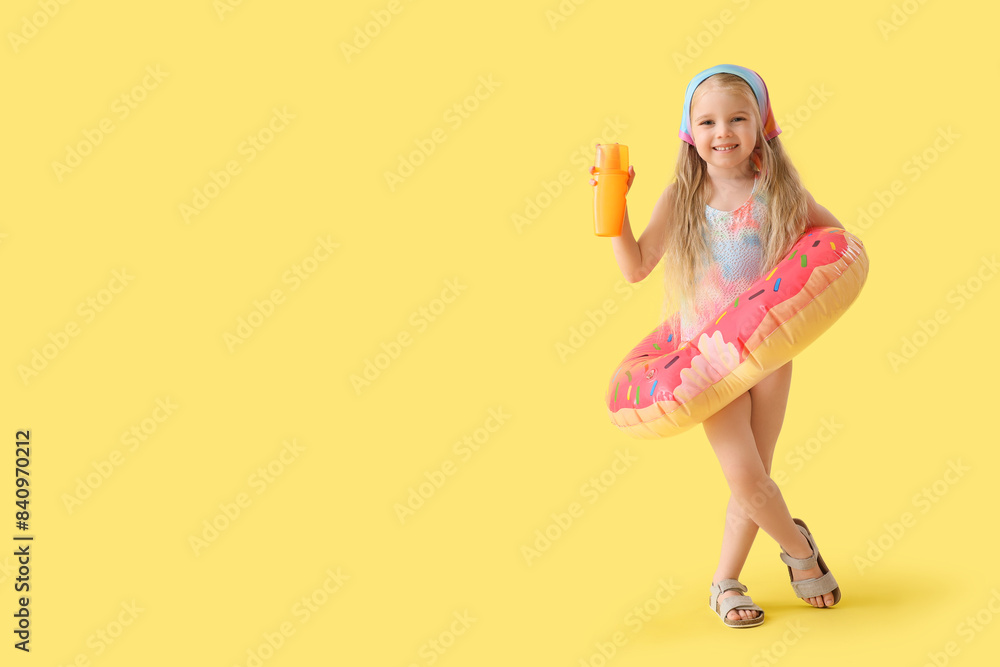 Cute little girl with sunscreen cream and swim ring on yellow background Cute little girl with sunscreen cream and swim ring on yellow background