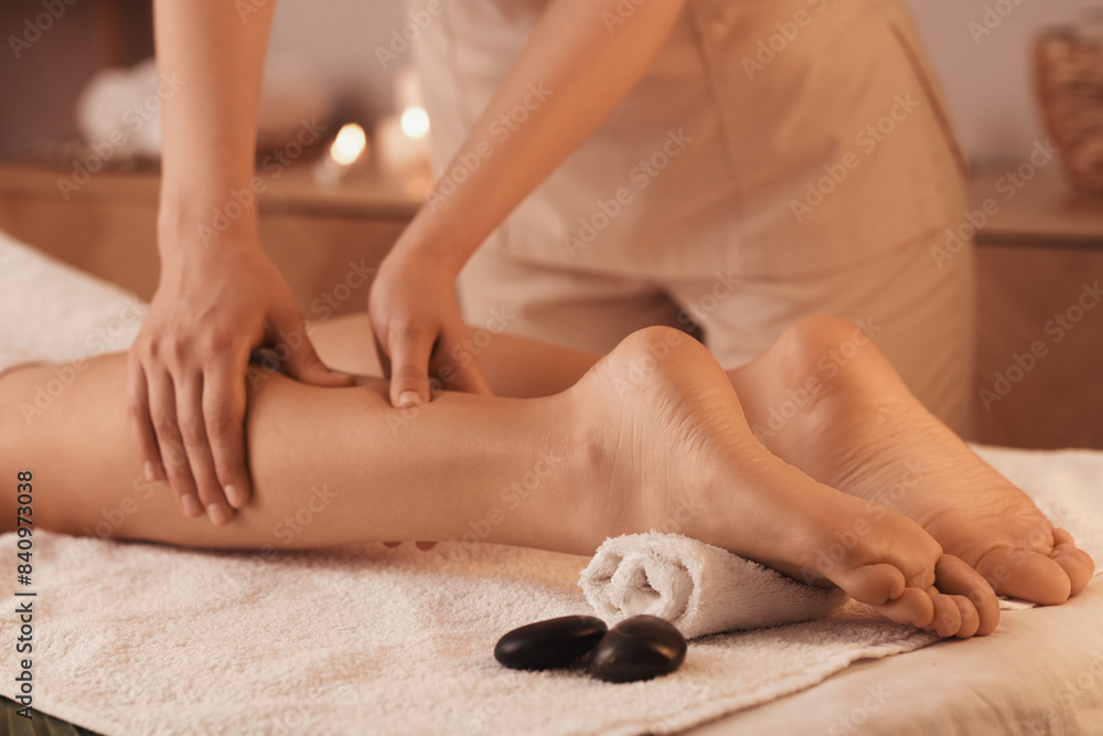 Obraz premium Young woman getting leg massage in dark spa salon, closeup