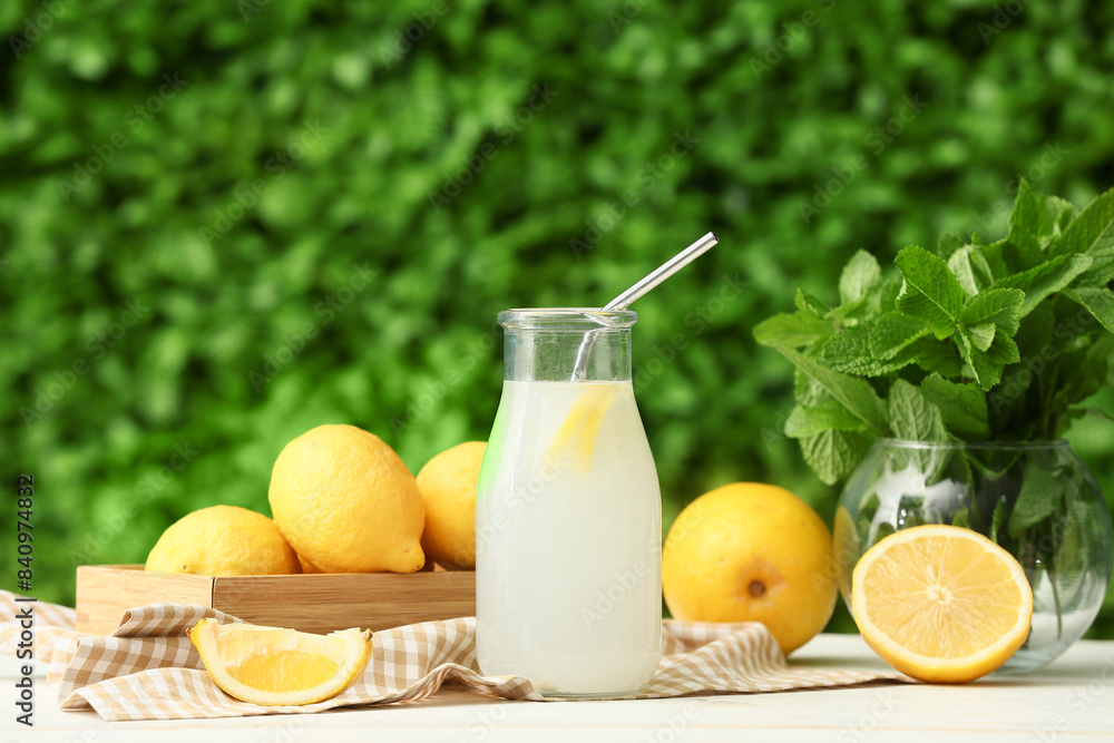 Bottle of fresh lemonade and vase with mint on white wooden table outdoors Bottle of fresh lemonade and vase with mint on white wooden table outdoors