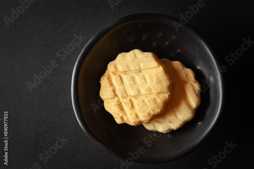 Carrom seed cookies or salted ajwain cookies are placed in a black bowl on a black background.