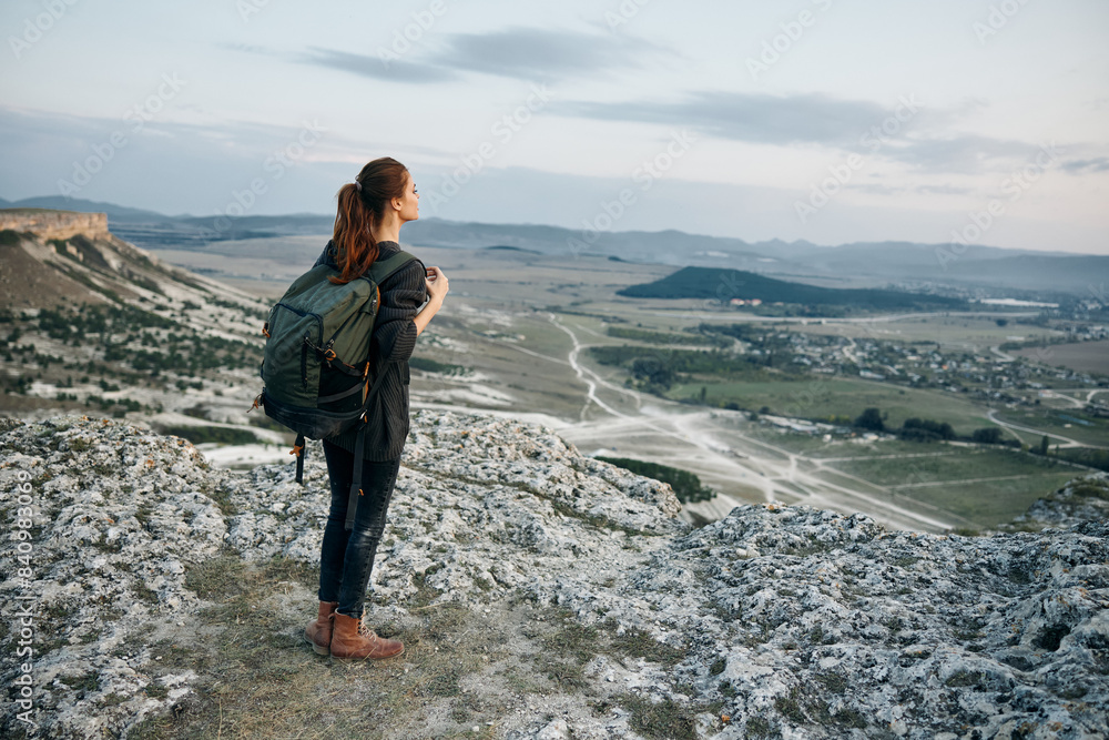 Fototapeta premium adventurous woman with backpack admiring stunning valley view from mountain peak