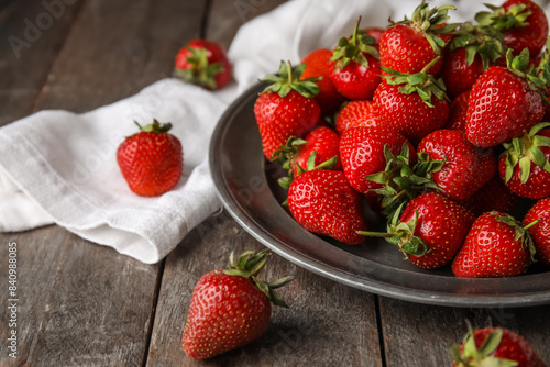 Plate with sweet fresh strawberries on wooden background