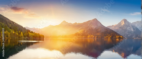 A beautiful lake surrounded by mountains with the sun rising over it.