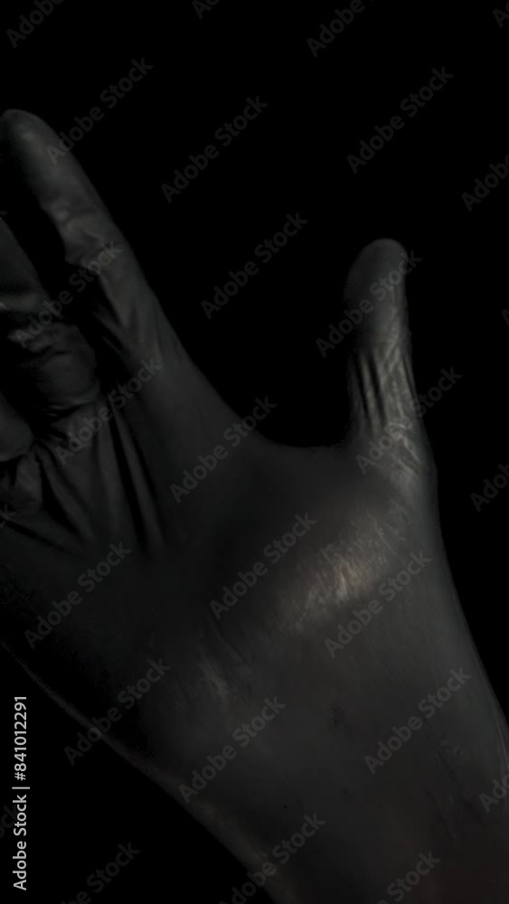 Vertical video. A Male Hand Puts on a Black Rubber Glove and Clenches It into a Fist. Slow Motion, Isolated. Vertical video. A Male Hand Puts on a Black Rubber Glove and Clenches It into a Fist. Slow Motion, Isolated.