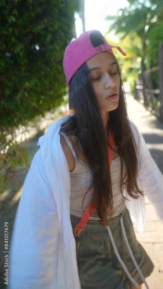 A young woman wearing a pink cap is enjoying a sunny day outside with casual and carefree vibes A young woman wearing a pink cap is enjoying a sunny day outside with casual and carefree vibes