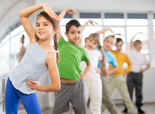 Dynamic little girl training in dancehall with trainer and other attendees of dancing courses